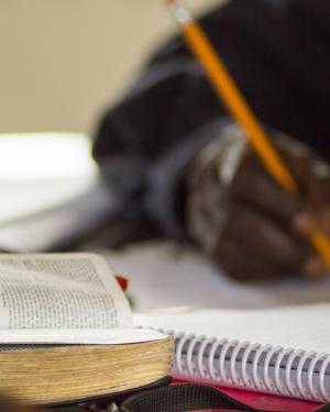 Man writing with a Bible on a desk.